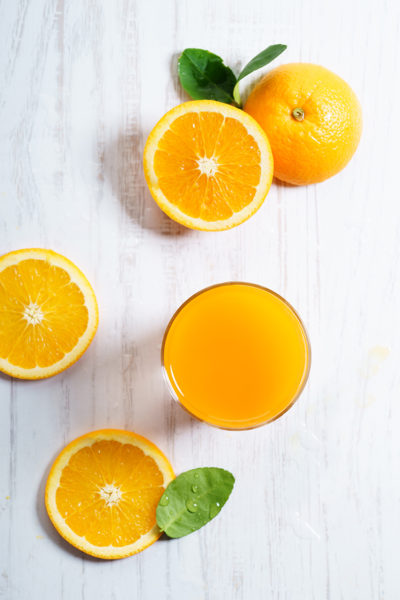 Glass of orange juice with sliced orange from above on white wooden background. fresh fruit product display.